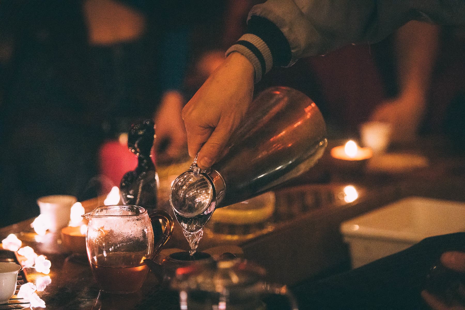 Hands pouring tea from a clay teapot